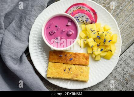 Mangobrot mit Joghurt auf pflanzlicher Basis und frischen Früchten, leuchtende Farben, bunte Mahlzeit, flaches Lay Stockfoto