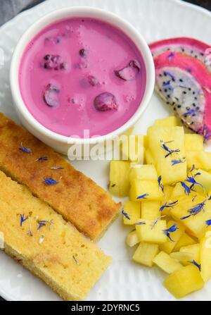 Mangobrot mit Joghurt auf pflanzlicher Basis und frischen Früchten, helle Farben, farbenfrohe Mahlzeit, Draufsicht, Nahaufnahme Stockfoto