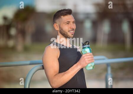 Mann Trinkwasser mit Zitrone aus wiederverwendbaren Flasche während einer Workout Stockfoto