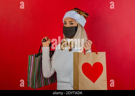 Modische Mädchen Einkaufen in weißem Kleid mit Gold Schutzmaske, Gold papillon und Weihnachtsmütze zur Prävention von Coronavirus Covid19 Pandemie. Stockfoto
