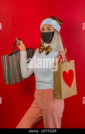 Modische Mädchen Einkaufen in weißem Kleid mit Gold Schutzmaske, Gold papillon und Weihnachtsmütze zur Prävention von Coronavirus Covid19 Pandemie. Stockfoto