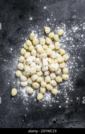 Ungekochte hausgemachte Gnocchi auf schwarzem Schneidebrett. Schwarzer Hintergrund. Draufsicht Stockfoto