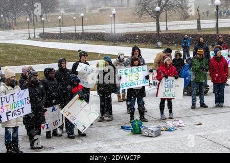 St. Paul, Minnesota. Die Menschen versammeln sich, um die Schulen wieder zu öffnen und Studenten während der Coronavirus-Pandemie an einem verschneiten Tag wieder in den Klassenzimmer zu bringen. Stockfoto