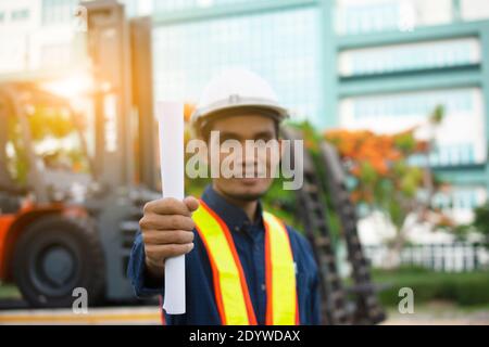 Engineering Holding Plan und trägt einen weißen Schutzhelm während der Arbeit. Hintergrundstruktur des Gebäudes Stockfoto