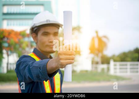 Engineering Holding Plan und trägt einen weißen Schutzhelm während der Arbeit. Hintergrundstruktur des Gebäudes Stockfoto