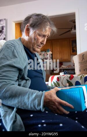 Eine 84-jährige Frau öffnet eines ihrer Geschenke am Weihnachtstag. Stockfoto