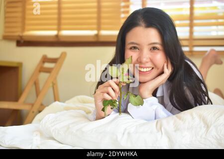 Schönheit Frauen weißes Hemd mit Rose ist auf Schlafzimmer, Junge Frauen schönes Lächeln in der Liebe Valentinstag Konzept Stockfoto