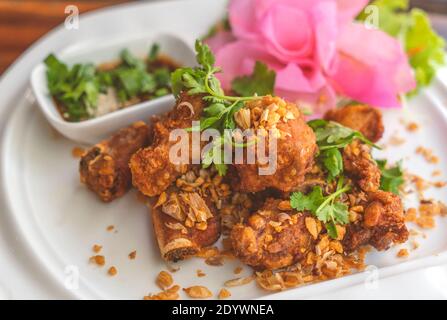 Frittierte Spare Ribs mit Knoblauch auf weißem Teller, schöne Dekoration, Nahaufnahme Thailand Speisekarte frittierte Spare Ribs. Stockfoto