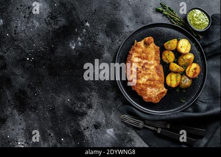 Panierte deutsche weiner Schnitzel mit Kartoffeln. Schwarzer Hintergrund. Draufsicht. Speicherplatz kopieren Stockfoto