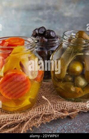 Fermentierte vegetarische Konserven Konzept. Eingelegte Gurken, schwarze Oliven und eingelegte Karotten in Gläsern. Das Konzept der Konserven Stockfoto