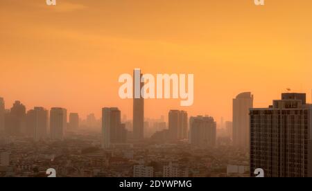 Luftverschmutzung in Bangkok, Thailand. Smog und feiner Staub von pm2.5 bedeckt Stadt am Morgen mit orange Sonnenaufgangshimmel. Stadtbild mit verschmutzter Luft. Stockfoto