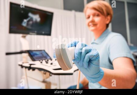 Konzentrieren Sie sich auf die Hände der Sonografin in sterilen Handschuhen, die den Ultraschallaufnehmer halten. Ärztin mit modernen Ultraschallscanner. Konzept der Ultraschall, medizinische Geräte, Ultraschall-Diagnostik Stockfoto