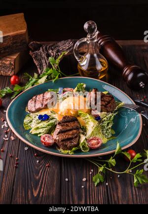 Eier benedikt mit Rindfleisch Fleisch auf einem großen weißen Teller.. Traditionelles englisches Frühstück mit Eiern Benedict, Kirschtomate, Salat. Benedict Ei serviert Stockfoto