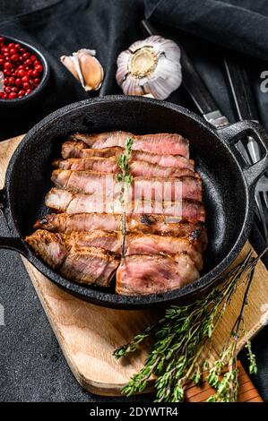 In Scheiben geschnittenes Schweinekotelett auf einem Knochen mit Gewürzen und Kräutern. Schwarzer Hintergrund. Draufsicht Stockfoto