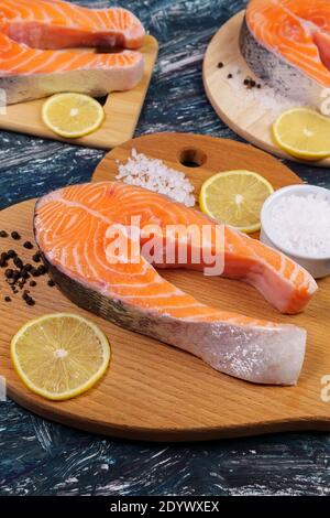 Lachssteak, reich an Omega-3-Öl, Zitrone und Meersalz auf schwarzem Hintergrund. Gesunde Ernährung und Ernährung. Stockfoto