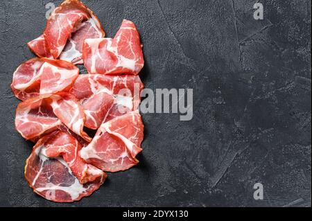 Italienischer Speck Pancetta Piacentina. Schweinefleisch. Schwarzer Hintergrund. Draufsicht. Speicherplatz kopieren Stockfoto
