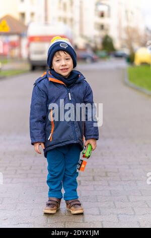 POSEN, POLEN - 25. Dezember 2020: Kleiner Junge mit einem Spielzeugzug, der auf einem Bürgersteig in der Stadt steht Stockfoto