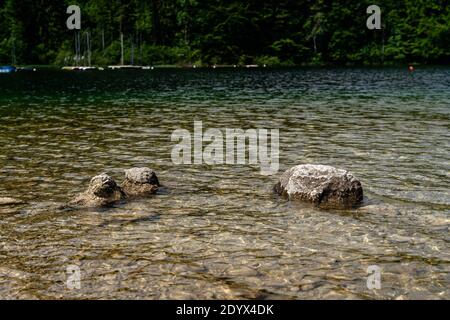 Schöne Aufnahme von See Bohinj mit mehreren großen Steinen auf Die Küste am Tag Stockfoto