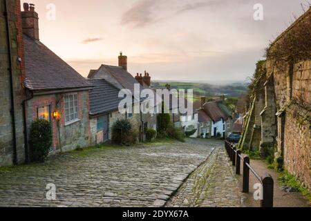 Shaftesbury, Dorset, Großbritannien. Dezember. Wetter in Großbritannien. Ein Blick auf Gold Hill in Shaftesbury in Dorset an einem kalten eisigen Morgen mit winterlichen Duschen kurz nach Sonnenaufgang. Bild: Graham Hunt/Alamy Live News Stockfoto