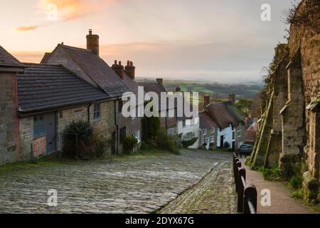 Shaftesbury, Dorset, Großbritannien. Dezember. Wetter in Großbritannien. Ein Blick auf Gold Hill in Shaftesbury in Dorset an einem kalten eisigen Morgen mit winterlichen Duschen kurz nach Sonnenaufgang. Bild: Graham Hunt/Alamy Live News Stockfoto