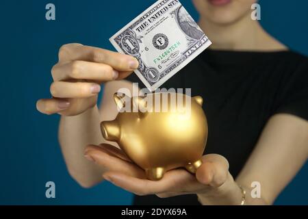 Frau in schwarzer Kleidung mit usa Dollar und Gold Sparschwein in den Händen. Stockfoto