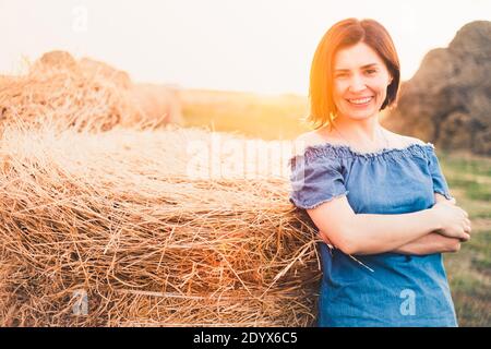 Lächelnde Frau in der Nähe von Heuhaufen im Freien auf dem Land Stockfoto