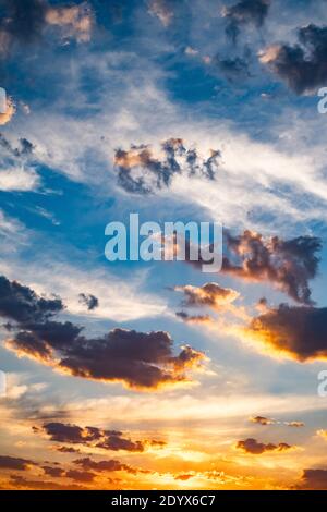 Flauschige blaue Wolken am Himmel und der orange Abend Untergehende Sonne Stockfoto