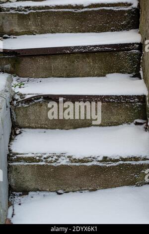 Die Steintreppe ist mit Schnee bedeckt. Konzept, der Winter ist gekommen, vorsichtig rutschig. Hochwertige Fotos Stockfoto