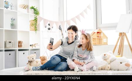 Lächelnde Mutter mit Tochter, die Selfie in niedlichen Kinderzimmer Stockfoto