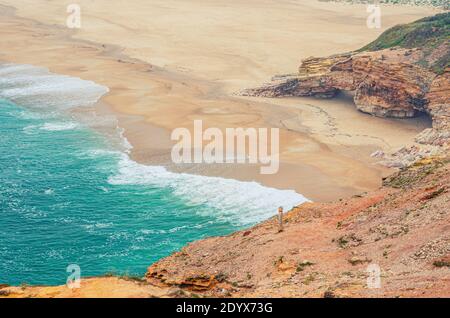 Top Luftaufnahme von Sandstrand mit Felsen und Klippen und Wellen von azurblauem türkisfarbenem Wasser des Atlantischen Ozeans in der Nähe von Nazare Stadt, Nordstrand Praia do Norte Stockfoto