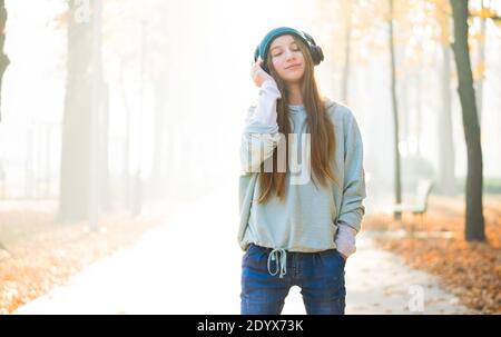 Nettes Mädchen, das Musik in Kopfhörern im Park hört Stockfoto