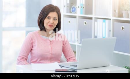 Lächelnde Geschäftsfrau, die im schönen Büro sitzt Stockfoto