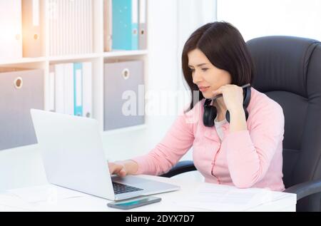 Hübsche Frau, die im modernen Büro am Laptop arbeitet Stockfoto