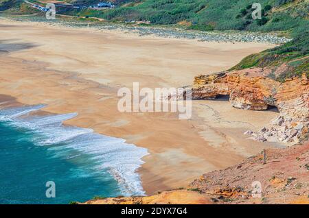 Top Luftaufnahme von Sandstrand mit Felsen und Klippen und Wellen von azurblauem türkisfarbenem Wasser des Atlantischen Ozeans in der Nähe von Nazare Stadt, Nordstrand Praia do Norte Stockfoto