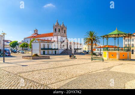 Heiligtum unserer Lieben Frau von Nazare katholische Kirche in Kopfsteinpflaster Platz mit Palmen in Sitio Hügel da Nazare Stadt, klaren blauen Himmel im sonnigen Sommer Stockfoto