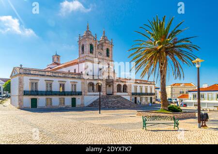 Heiligtum unserer Lieben Frau von Nazare katholische Kirche in Kopfsteinpflaster Platz mit Palmen in Sitio Hügel da Nazare Stadt, klaren blauen Himmel im sonnigen Sommer Stockfoto