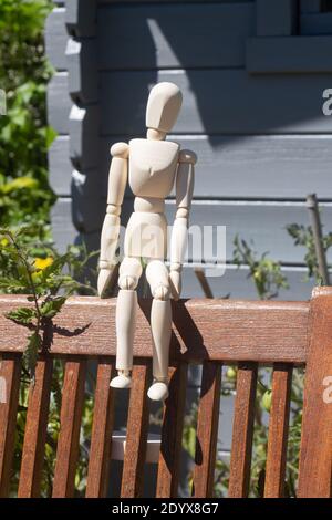 Hölzerne Schaufensterpuppe zum Zeichnen auf einem Stuhl sitzend Stockfoto