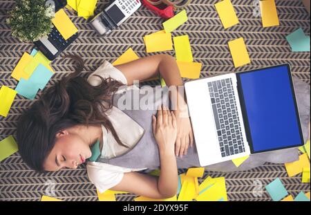 Erschöpfter Freiberufler, der ein Nickerchen im Schlafen auf dem Boden im Heimbüro macht. Attraktive Frau zu Hause Stockfoto