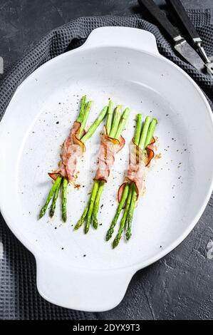 Leckerer Schweineback um Spargel in einer Backform. Schwarzer Hintergrund. Draufsicht Stockfoto