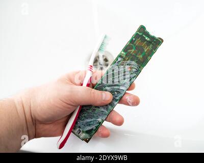 Reinigen der Platine von der Fernbedienung des Fernsehers mit einer Zahnbürste, Schaum und Seife. Wiederherstellung der Funktionalität von elektronischen Komponenten. Stockfoto