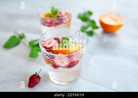 Sommercocktail mit Erdbeere, Orange und Minze im Glas auf weißem Tisch, hausgemachte erfrischende Limonade, Erdbeerpunsch, Kopierraum. Stockfoto