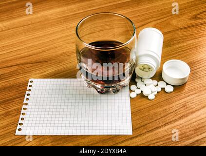 Glas des Whiskeys mit einem Pills und leerem Papier Auf dem Tisch Nahaufnahme Stockfoto