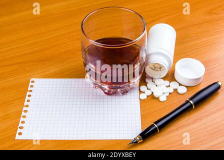 Glas des Whiskeys mit einem Pills und leerem Papier Auf dem Tisch Nahaufnahme Stockfoto