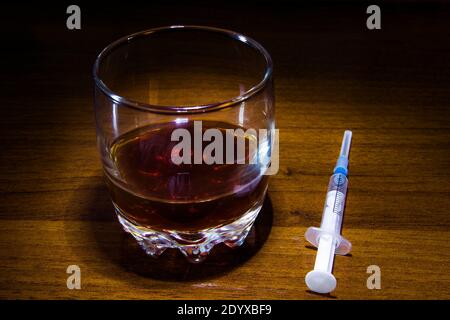Ein Glas Whiskey und eine Spritze auf dem Tisch Nahaufnahme Stockfoto