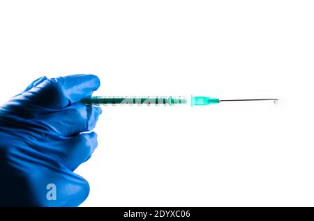 Spritze mit einem Tropfen in der Hand eines Arztes mit blauen Handschuhen. Weißer Hintergrund. Speicherplatz kopieren. Covid-19-Impfung. Stockfoto