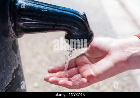 Wasser aus dem Wasserhahn läuft auf der Hand Stockfoto