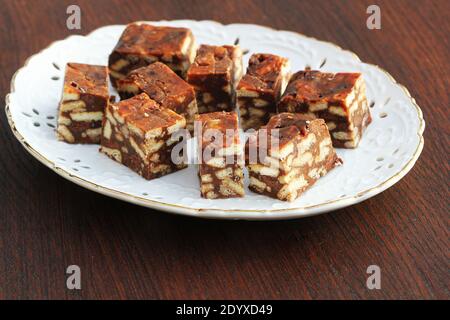 Fauler Kuchen oder Mosaikkuchen . Hausgemachter, nicht gebackener Schokoladenkuchen auf einem Holztisch Stockfoto