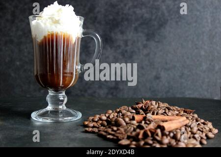 Schaumig Kaffee trinken. Cappuccino oder Latte in einem transparenten Glas auf dunklem Grund Stockfoto