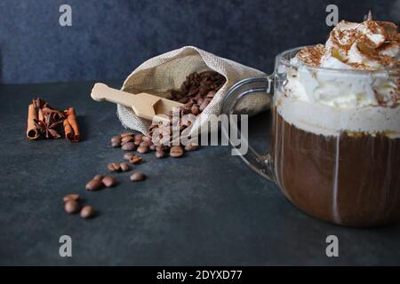 Schaumig Kaffee trinken. Cappuccino oder Latte in einem transparenten Glas auf dunklem Grund Stockfoto