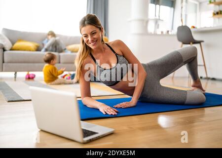 Junge Frau übt Yoga zu Hause aus. Fitness, Workout, gesundes Leben und Diät-Konzept. Stockfoto
